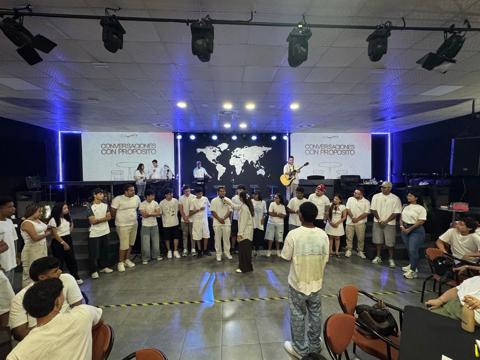 Jóvenes reunidos en círculo en el escenario durante el cierre de la reunión FreeLife