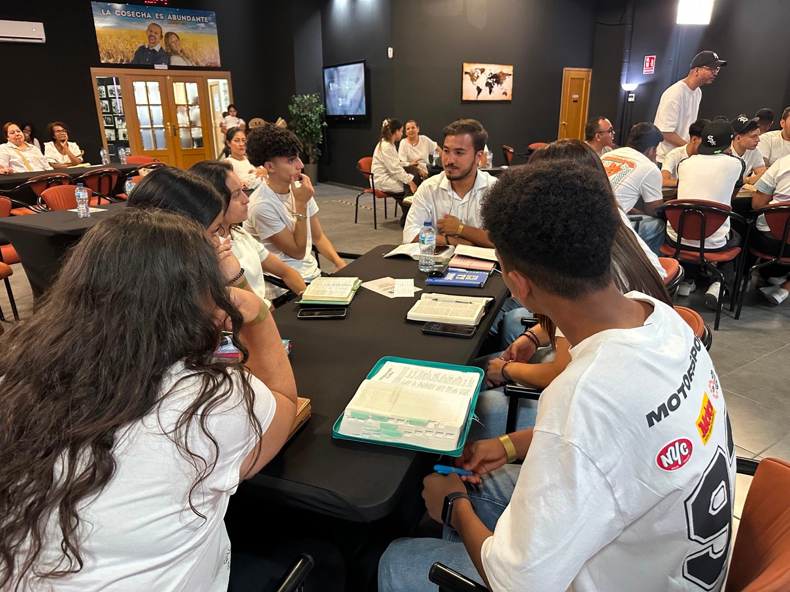 Jóvenes conversando alrededor de una mesa con Biblias abiertas durante la noche de Conversaciones con Propósito